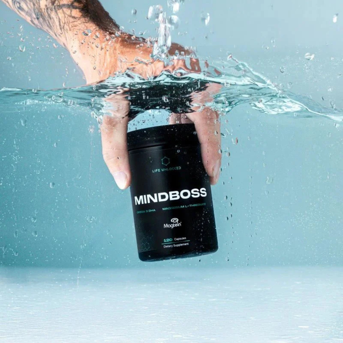 Hand holding a 'MINDBOSS' supplement container underwater with a light blue background